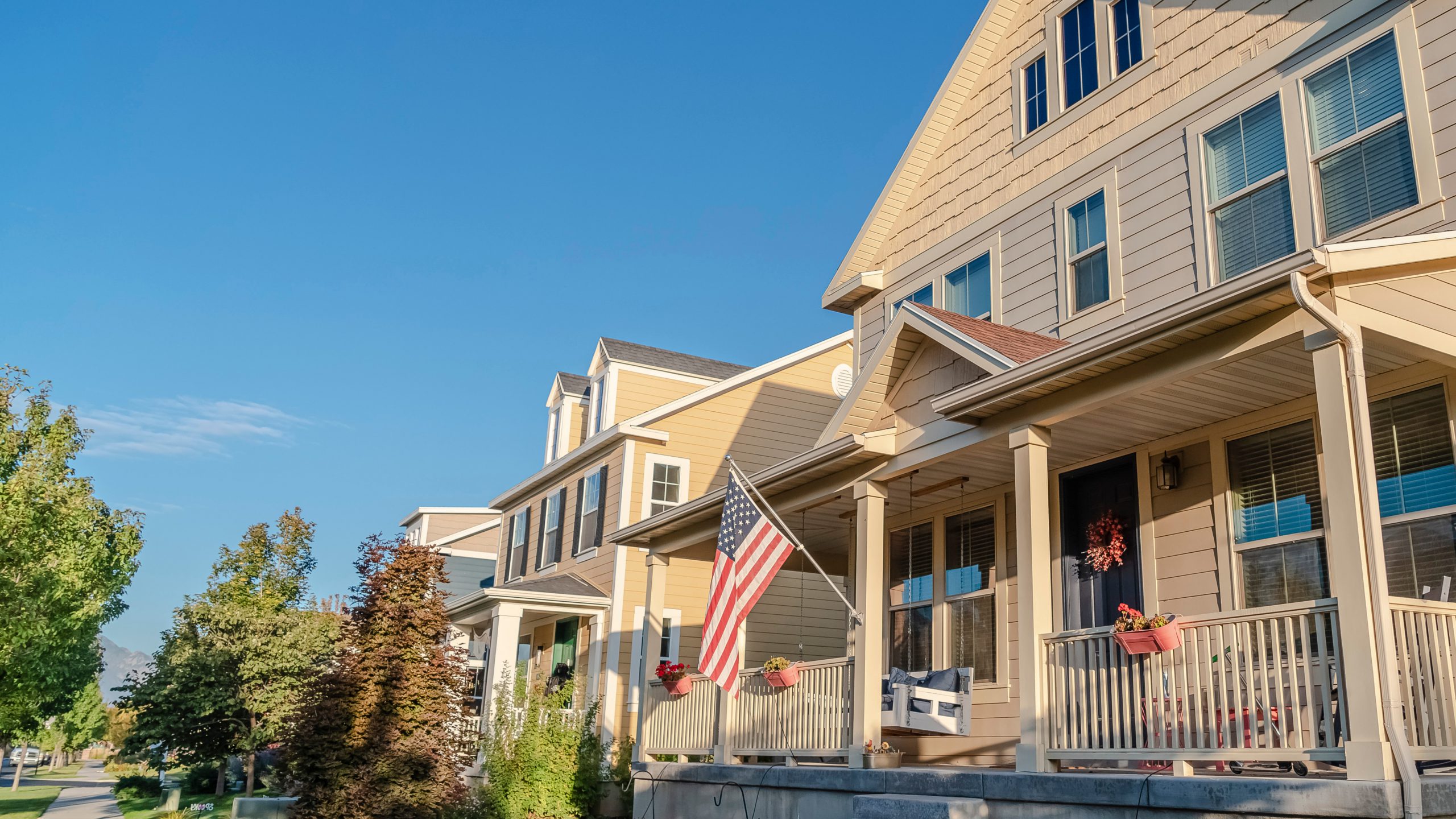 Panorama American flag flying from a front porch of a house in a long receding row of urban properties on a quiet street