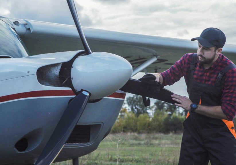 Aircraft mechanic polishing plane and then standing satisfied with his job.